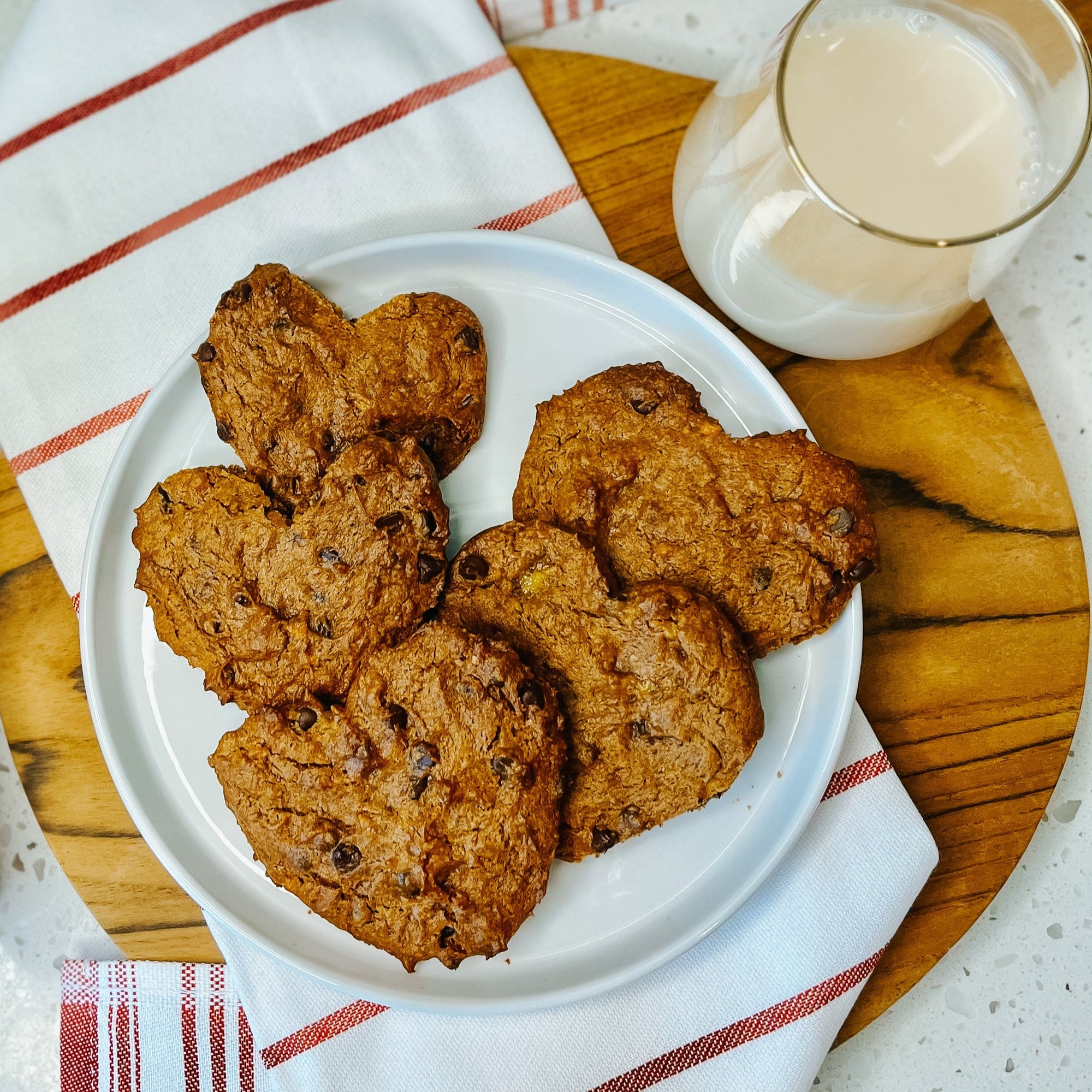 PB2 Pantry Chocolate Chip Cookies made into hearts on a plate with a glass of milk next to them